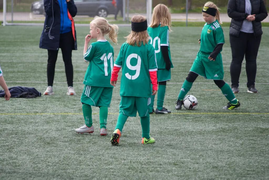 Barn i gröna träningströjor övar med boll på föreningens fotbollsskola