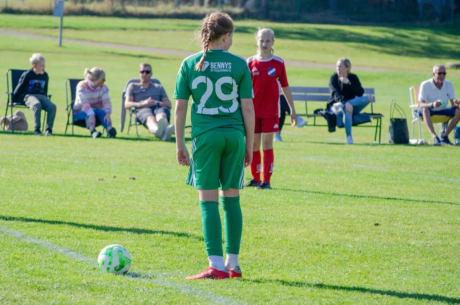 Ung spelare i grön matchtröja lägger en frispark under en ungdomsmatch